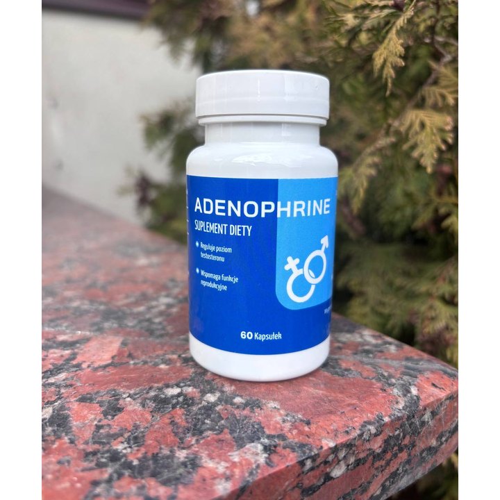 Adenophrine — biała butelka z niebieską etykietą, symbolami płci i napisem 60 Kapsułek, na kamiennym parapecie